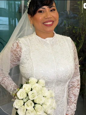 Noiva com vestido de renda manga longa, véu e buquê de rosas brancas
