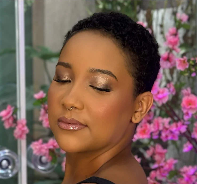 Produção em cabelo curto natural, pele iluminada e brilho dourado nos olhos