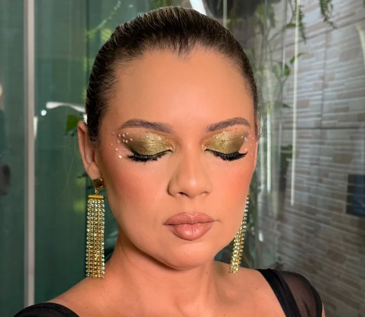 Olhos fechados com glitter dourado e pedrarias aplicadas na pálpebra