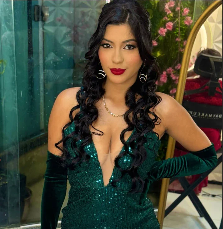 Produção com vestido verde de paetês, cachos longos e batom vermelho